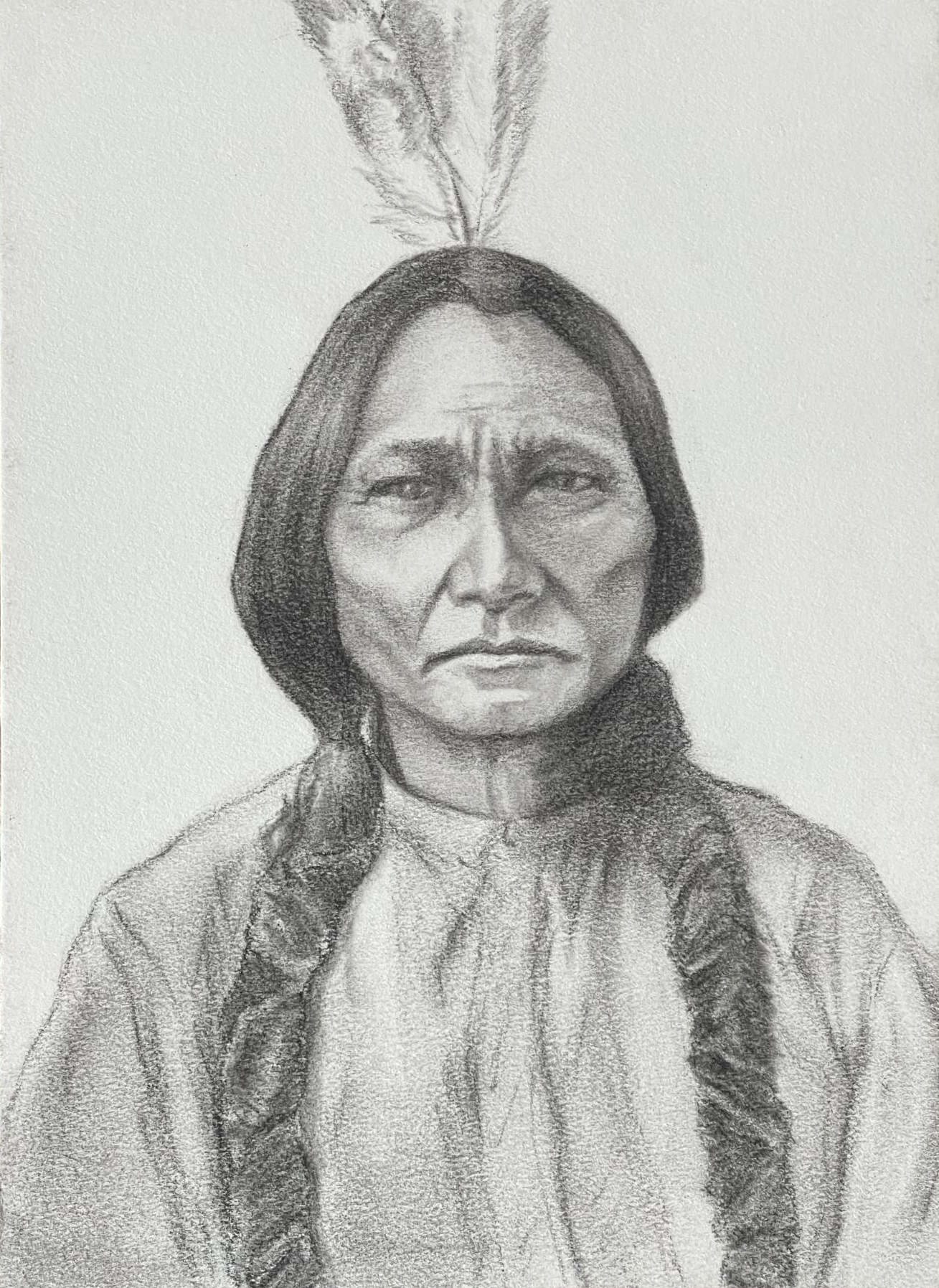Full frontal portrait of Geronimo in middle age. His long hair is in braids falling in front of his chest and he has two eagle feathers sticking out of the back of his hair.