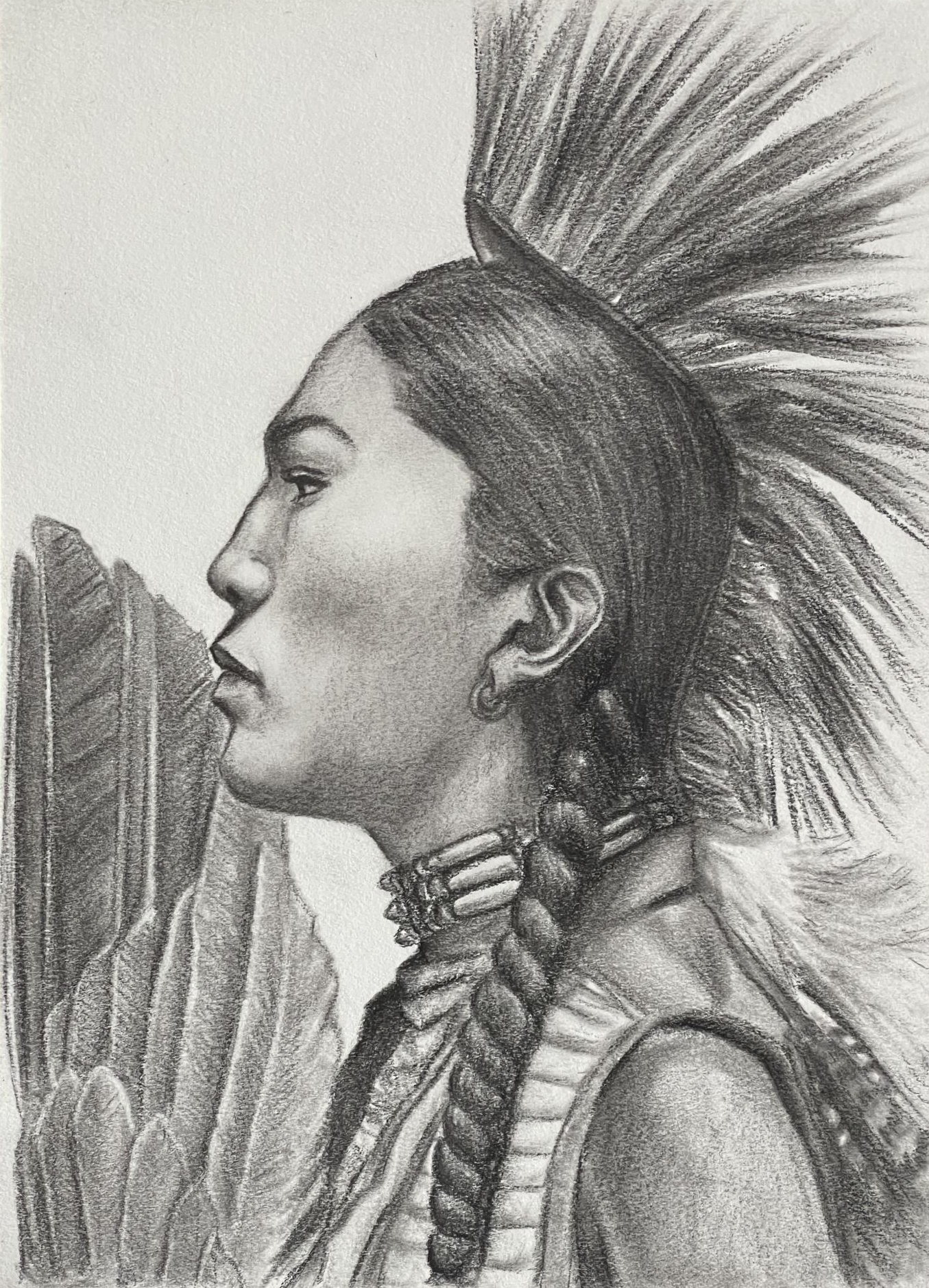 Young Native American woman shown in profile wearing a ceremonial dress and holding an eagle feather fan.