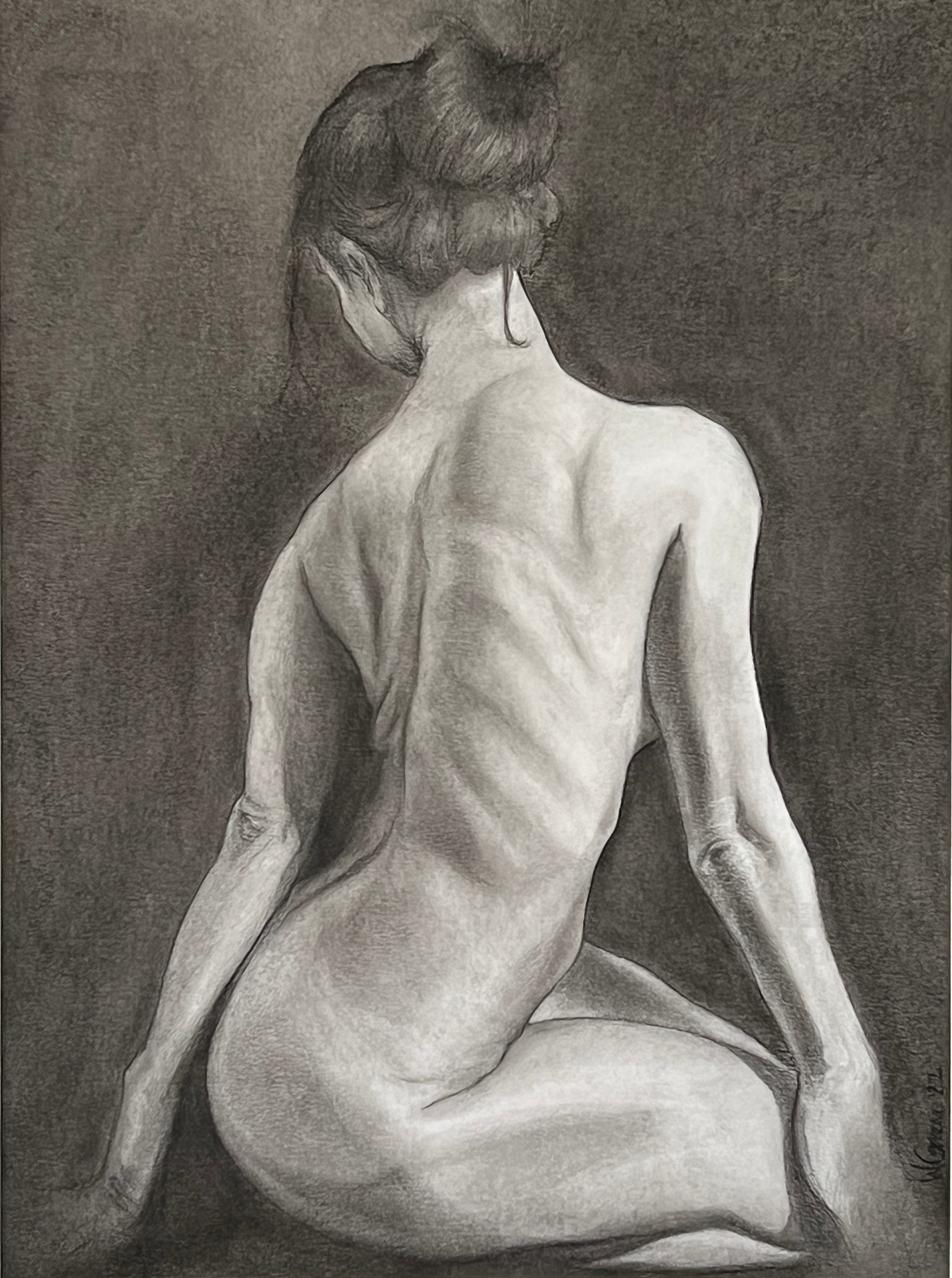 Caucasian woman from behind, kneeling with her back straight looking down and away from the viewer.